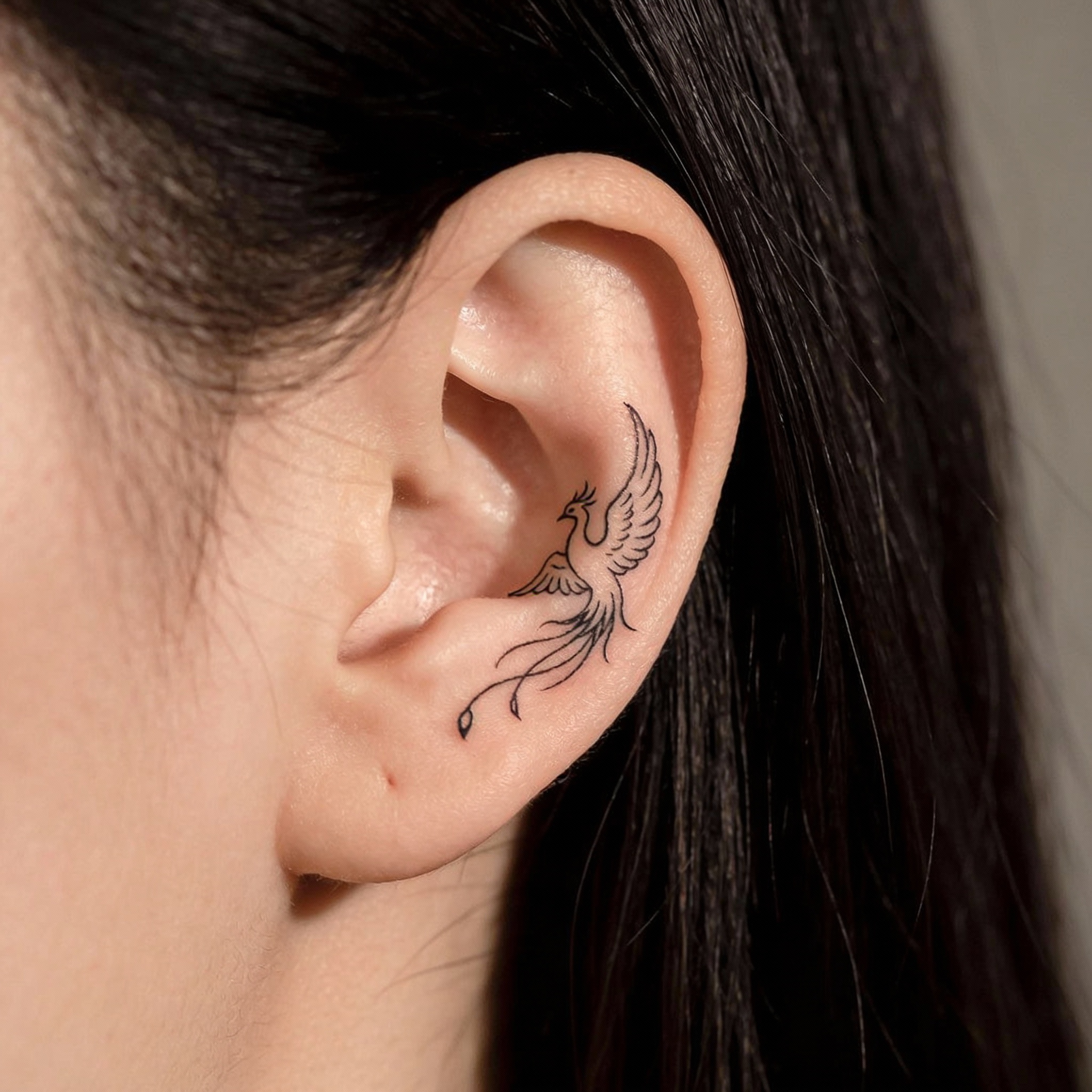 Small phoenix tattoo behind the ear